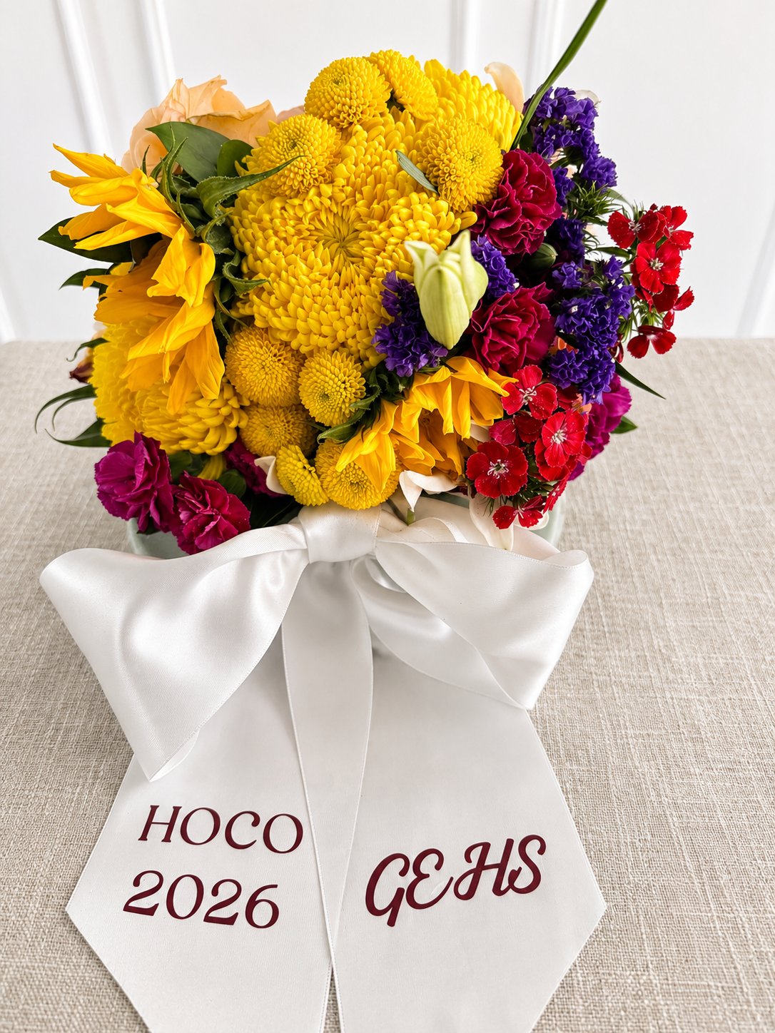 Bright yellow, red, and purple homecoming bouquet with a printed school sash