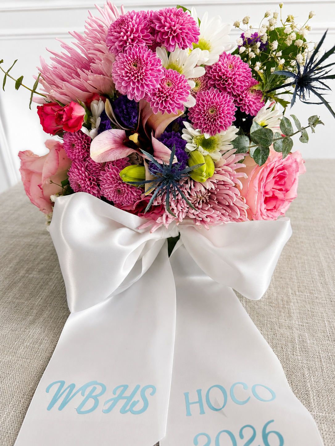 Blush and lavender pastel homecoming bouquet with a printed school sash